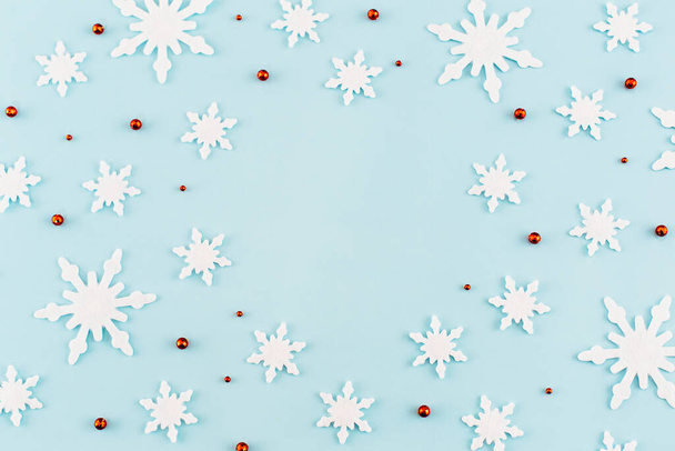 Christmas composition. Pattern made of snowflakes, red decorations on blue background. Christmas, winter, new year concept. Minimal style. Flat lay, top view.  - Foto, afbeelding