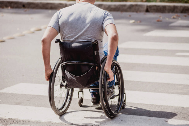 Handicapped man in wheelchair crossing street road - Фото, изображение