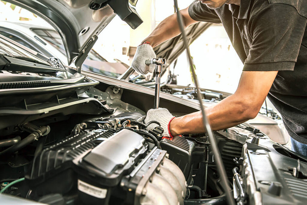 Zbliżenie ręce mechanika samochodowego są za pomocą klucza do naprawy silnika samochodu w garażu samochodowym. Koncepcje naprawy i usług stałych w zakresie opieki samochodowej. - Zdjęcie, obraz