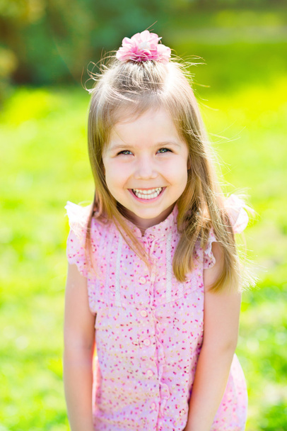Adorable laughing little girl with long blond hair, outdoor portrait in summer park - Photo, Image