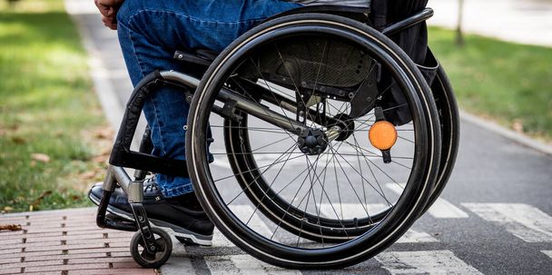 Handicapped man in wheelchair preparing to cross the road on pedestrian crossing - Foto, Imagen