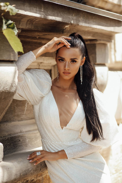 fashion outdoor photo of beautiful woman with dark hair in luxurious wedding dress and accessories posing in the summer street - Φωτογραφία, εικόνα