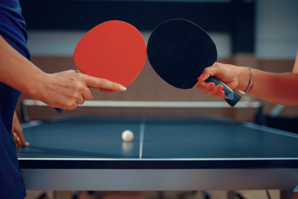 Les femmes tiennent des raquettes de ping-pong, des joueuses de tennis de table. Amis jouant au tennis de table à l'intérieur, jeu de sport avec balle, mode de vie sain et actif - Photo, image
