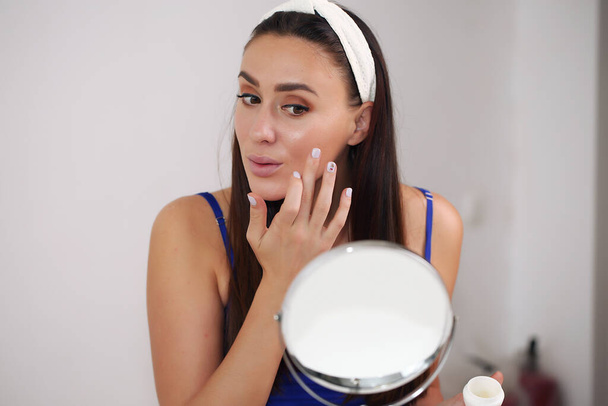 girl applying moisturizer on face. Skin care and beauty concept - Fotó, kép