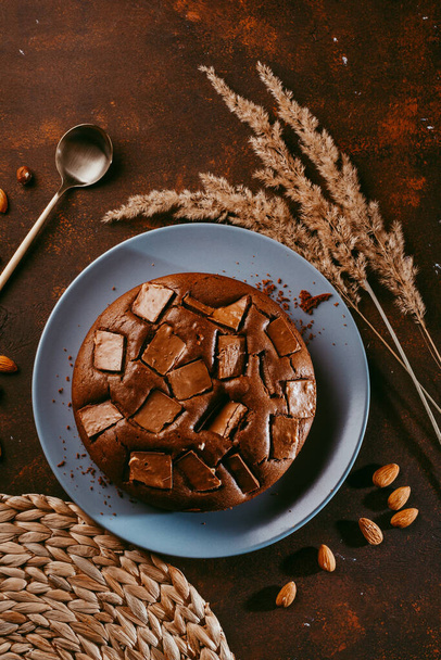 Chocolate cake with chocolate pieces on a brown table background - Zdjęcie, obraz