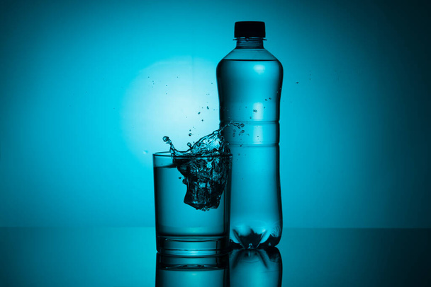 bottle of water with a glass on a blue background - Photo, image