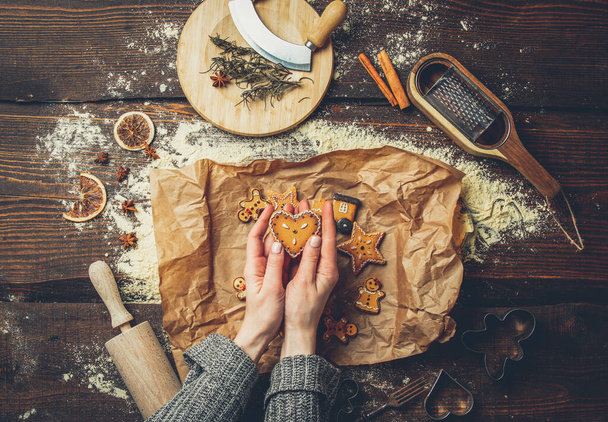Руки женщины держат печенье рядом с мукой и бумагой на столе  - Фото, изображение