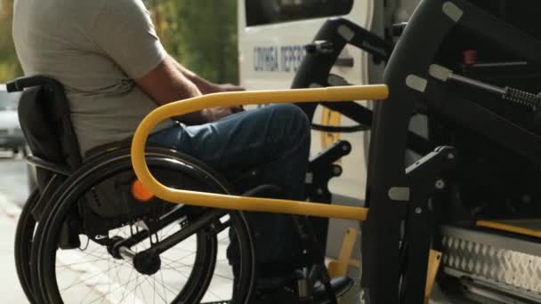 Egy tolószékes férfi, aki a fogyatékos emberek kocsijának a liftjében ül. Emelőberendezések mozgássérültek számára - kerekesszékes férfi a jármű közelében - Felvétel, videó