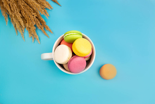 French multicolored macaroons in a white teacup. Dessert. - Photo, image