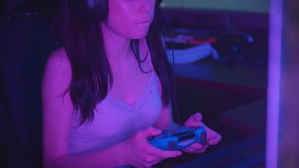 Junge Frau spielt Spiele in Neon-Spielclub und pustet einen Bubblegum - hält einen Steuerknüppel - Filmmaterial, Video