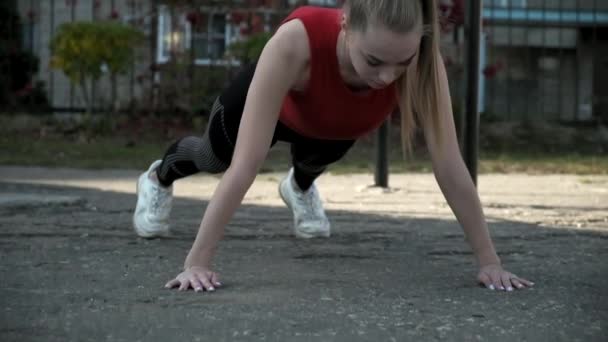 Junge, fitte hübsche Frau in Sportbekleidung turnt auf Sportplatz im Freien - Filmmaterial, Video