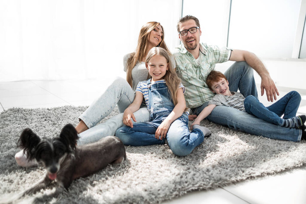 happy family with pet sitting on the carpet - Фото, изображение