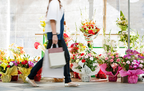 Mujer caminando pasado flores mercado
 - Foto, Imagen