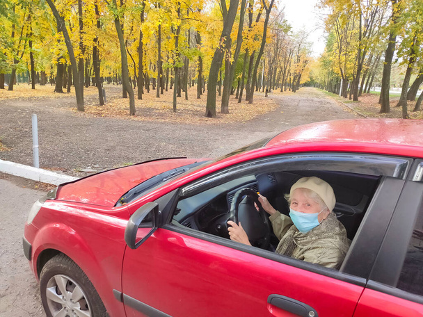 Vanhempi valkoihoinen nainen kasvonaamioineen autossa. Nainen eläkeläinen naamiossa suojellakseen itseään COVID19-virukselta. - Valokuva, kuva