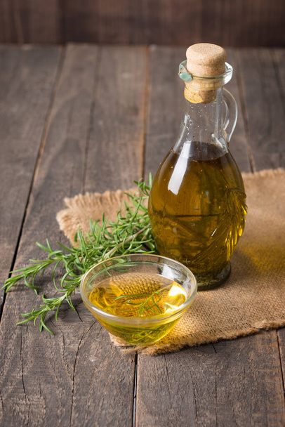 Rosemary oil on wooden background. Natural food concept.  - Фото, изображение