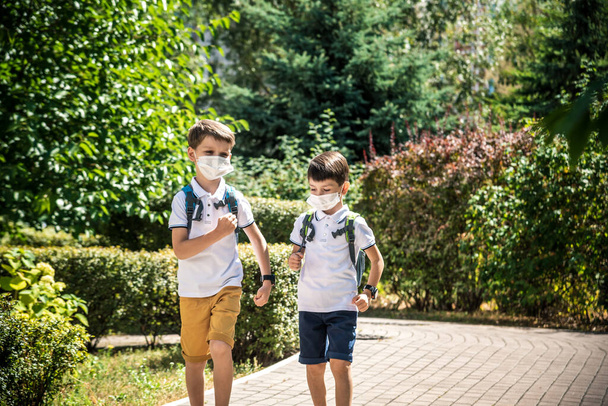 Niños felices con máscaras faciales huyen de la alegría de regresar a la escuela durante la cuarentena Covid-19. - Foto, Imagen