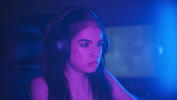 Junge attraktive Frau sitzt im Neon-Gaming-Club und spielt Spiele - beißt sich in die Lippe - gewinnt das Spiel und wird glücklich - Filmmaterial, Video