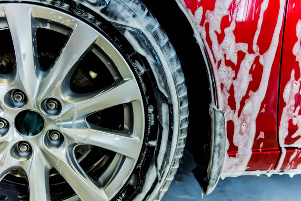 Lavado de coche rojo con espuma activa en el servicio de lavado de coches. - Foto, Imagen