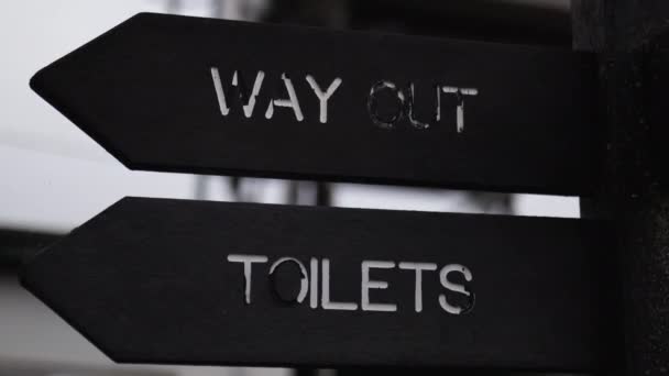 Dřevěná tyč s nápisem, kde jsou toalety a východ - Záběry, video