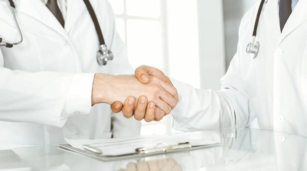 Two doctors are shaking hands as agreement about patients treatment, close-up. Medical help, medicine concept - Foto, immagini