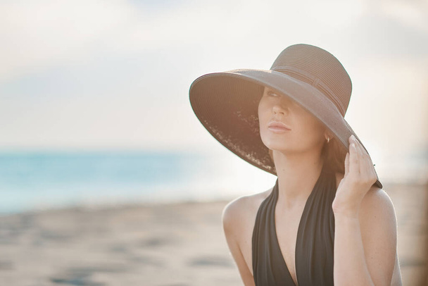 Žena s kloboukem na hlavě hledící na moře - Fotografie, Obrázek