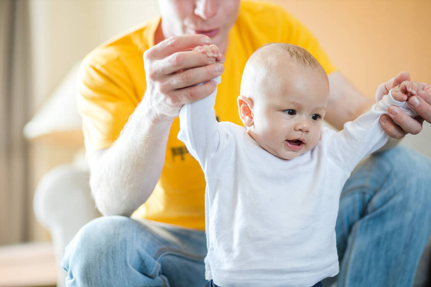 Happy father playing with adorable baby in the room at home. - Photo, image