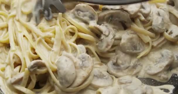 Смешивание спагетти-пасты с грибным соусом на сковородке на красной камере - Кадры, видео