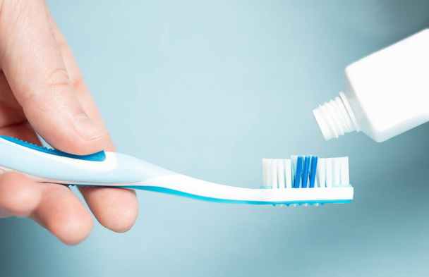 Een jonge vrouw met een blauwe tandenborstel. Een vrouw die haar tanden poetst. Gezondheidsconcept. - Foto, afbeelding