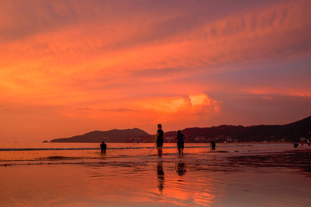 People come out to trawl their nets on Patong beach during sunset time - Photo, Image