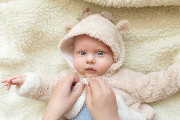 Mom's hands dressing her cute little son in a deer suit - Photo, Image