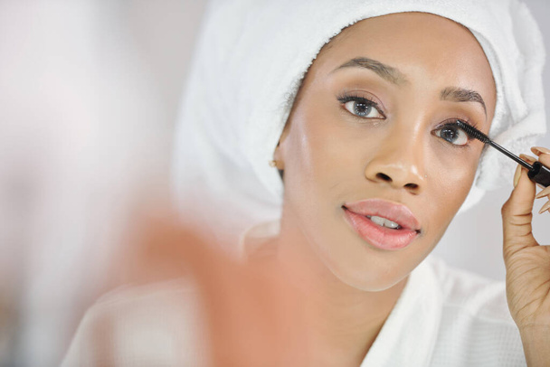 Gorgeous attractive young woman in bathrobe applying volumizing mascara - Photo, Image