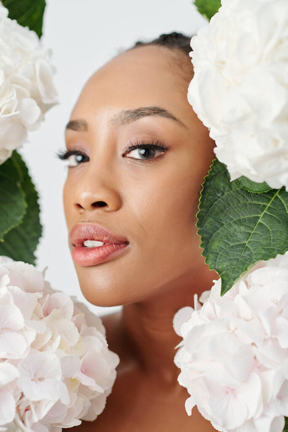 Jeune femme avec une peau impeccable debout avec des fleurs d'hortensia autour - Photo, image