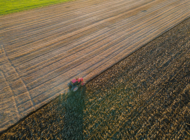 Αεροφωτογραφία του γεωργού που εργάζεται σε ελκυστήρα και προετοιμάζει γη για σπορά - Φωτογραφία, εικόνα