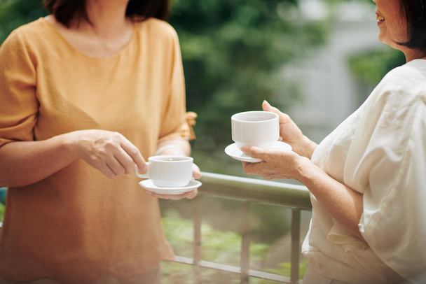Обрезанный образ пожилых женщин, пьющих чай и обсуждающих новости на встрече - Фото, изображение