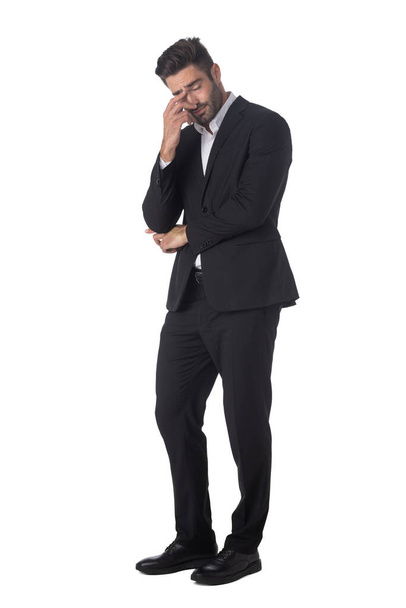 Full length portrait of young handsome business man in black suit feeling stress or depression studio isolated on white background - Photo, image