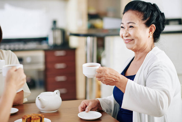 Щаслива жінка з В "єтнаму п" є гарячий чай, коли проводить день з друзями або родичами. - Фото, зображення