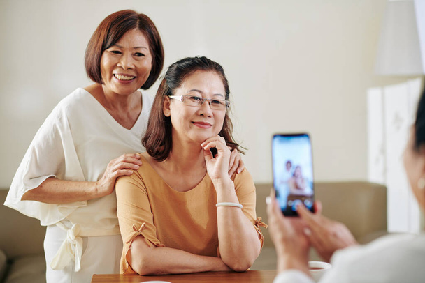 Mujer tomando fotos de sus amigas ancianas muy sonrientes - Foto, Imagen