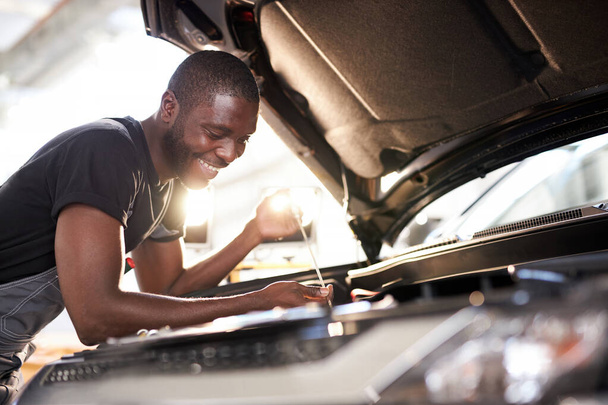 cheerful smiling afro man enjoy repairing cars hood - Foto, imagen