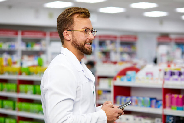 side view on pharmacist man using smartphone at work - Foto, imagen