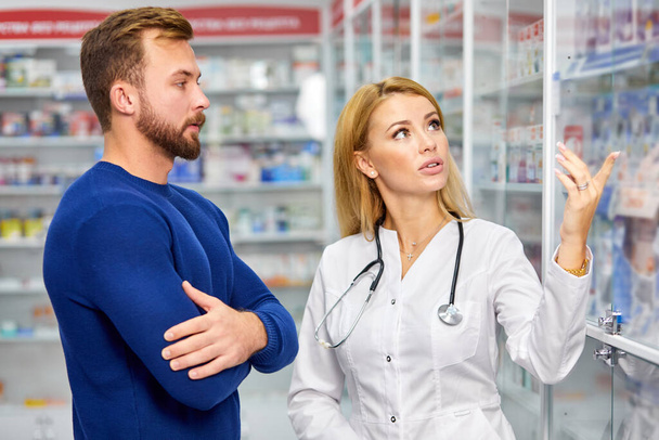 caucasian friendly pharmacist has a nice conversation with a client, helps to find a medication - Fotó, kép