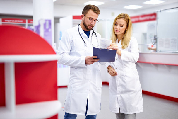 two caucasian pharmacists are discussing medication, using a digital tablet - Fotografie, Obrázek