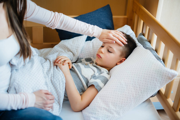 A mother takes care of her child who has a fever and fever. Disease and healthcare - Фото, зображення