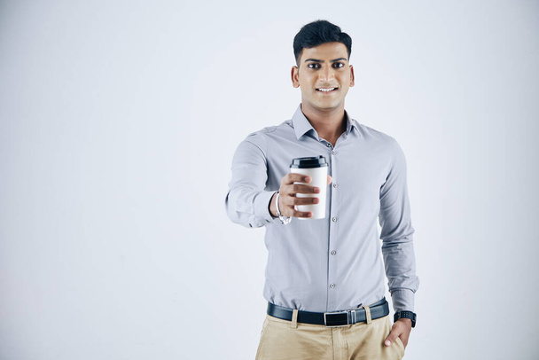 Studio portret uśmiechnięty młody indyjski biznesmen dając filiżankę cappuccino - Zdjęcie, obraz