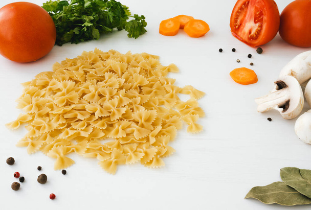 Closeup of macaroni with vegetables on bright wooden background. Cooking concept - Photo, Image