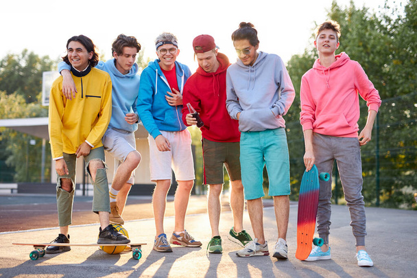 portrait of friendly team of sportive teenagers holding basketball ball and skateboard - Foto, immagini