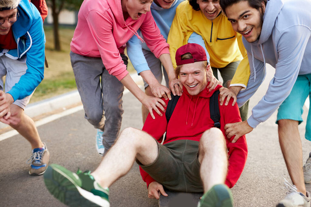 gars amicaux modernes en vêtements décontractés skateboard et montrant des astuces passionnantes - Photo, image