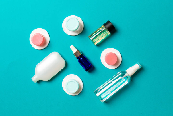 Top view of means for face care: bottles and jars of tonic, micellar cleansing water, cream, cotton pads on colored background. Bodycare concept with empty cpace for your ideas. - Photo, Image