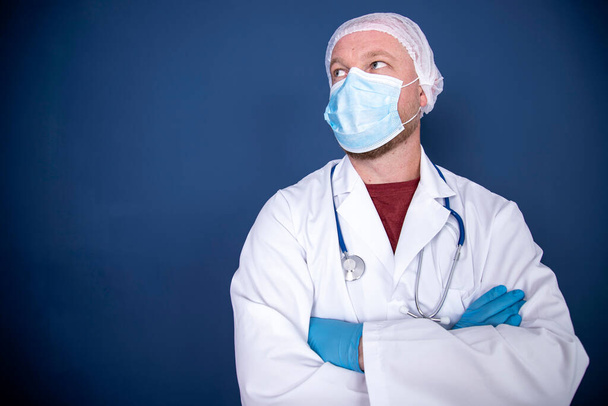 Medicine, profession and healthcare concept - close up of male doctor or scientist in protective facial mask over blue background - Foto, Imagem
