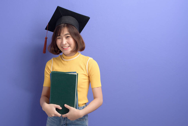 A portrait of young Asian student wearing graduation cap over studio background. - Фото, зображення