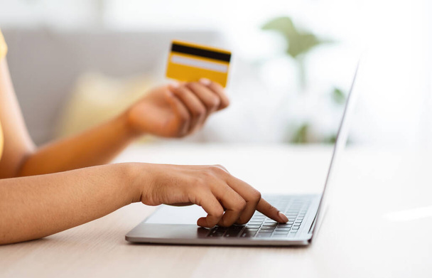 Μαύρη γυναίκα που χρησιμοποιεί φορητό υπολογιστή και πιστωτική κάρτα στο σπίτι - Φωτογραφία, εικόνα